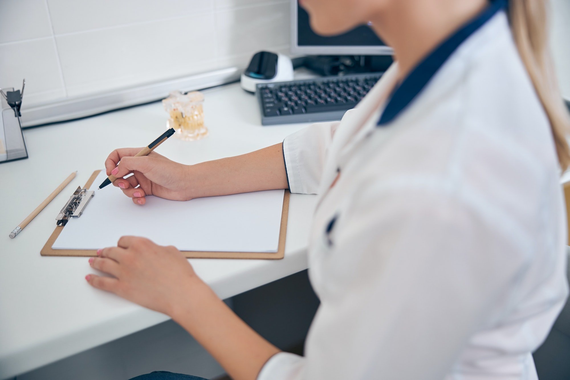 Woman in medical uniform writing at desk